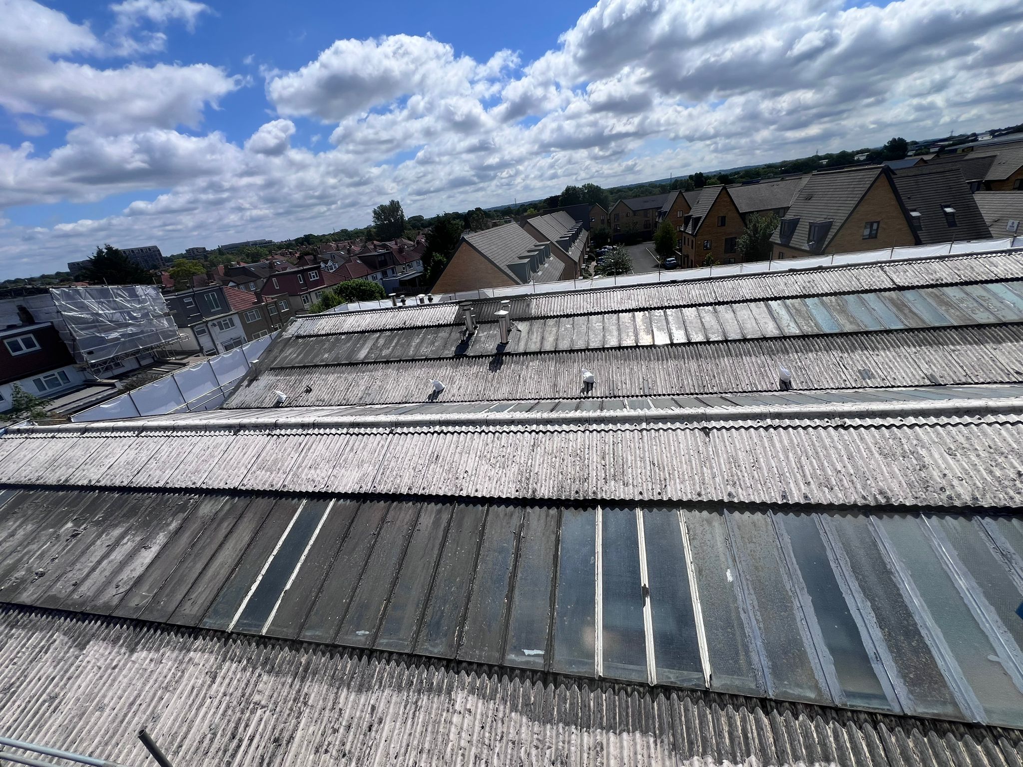 A weathered commercial roof with degraded sheets and rooflights before coating
