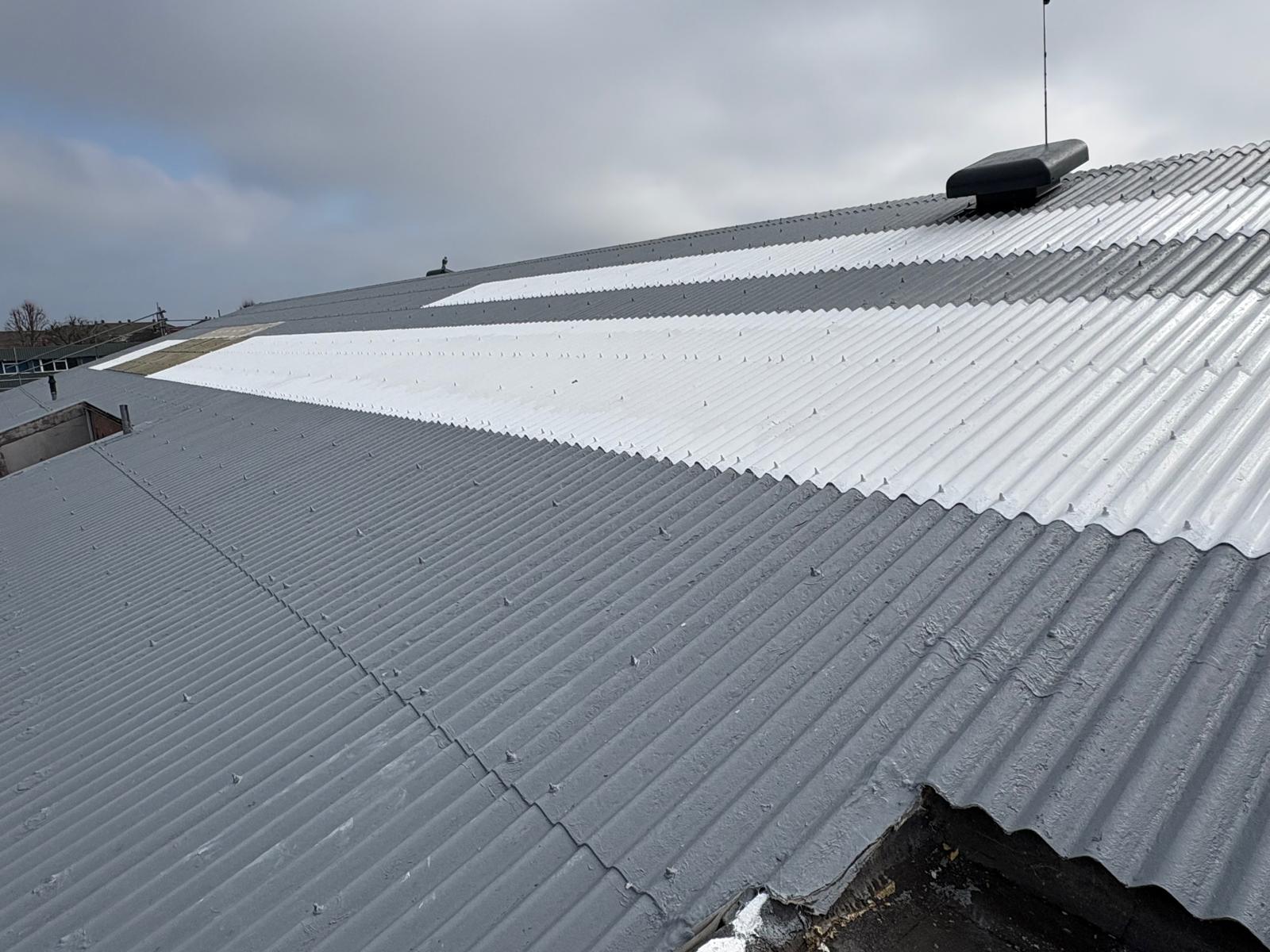 Freshly coated asbestos roof sections in light grey silicone