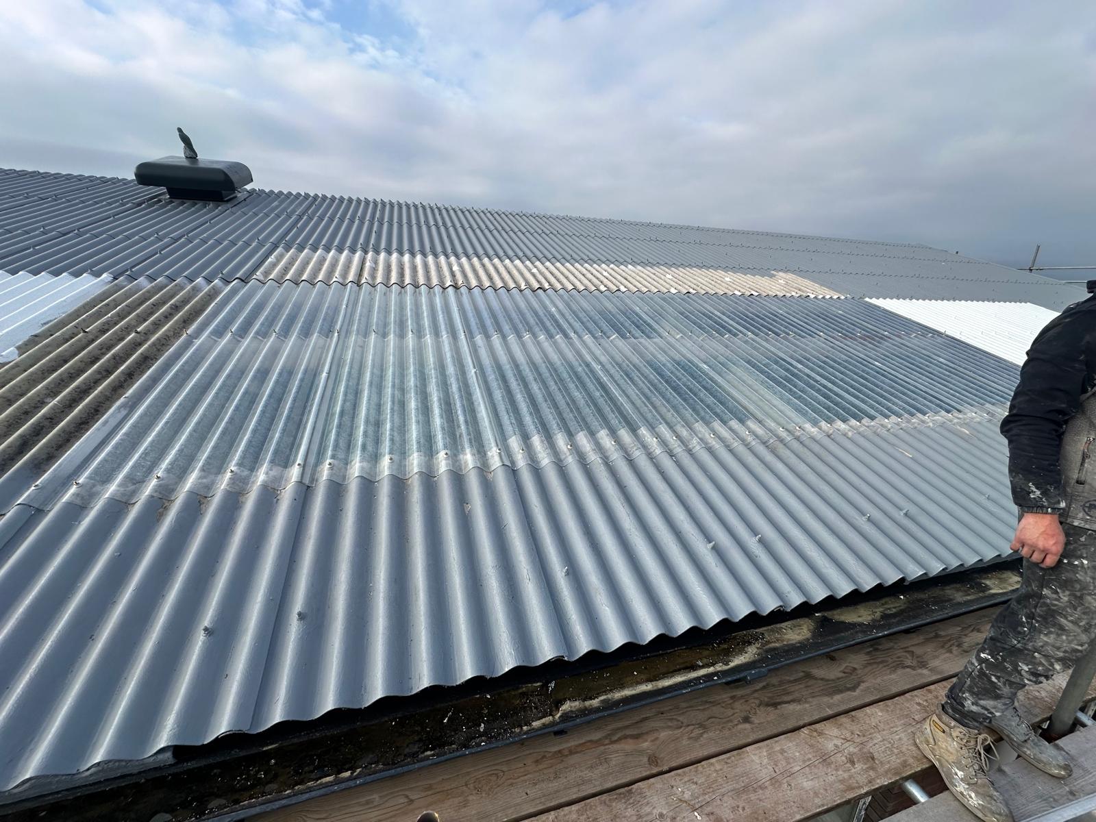 GacoFlex silicone coating mid-application on a commercial roof, half the sheets coated
