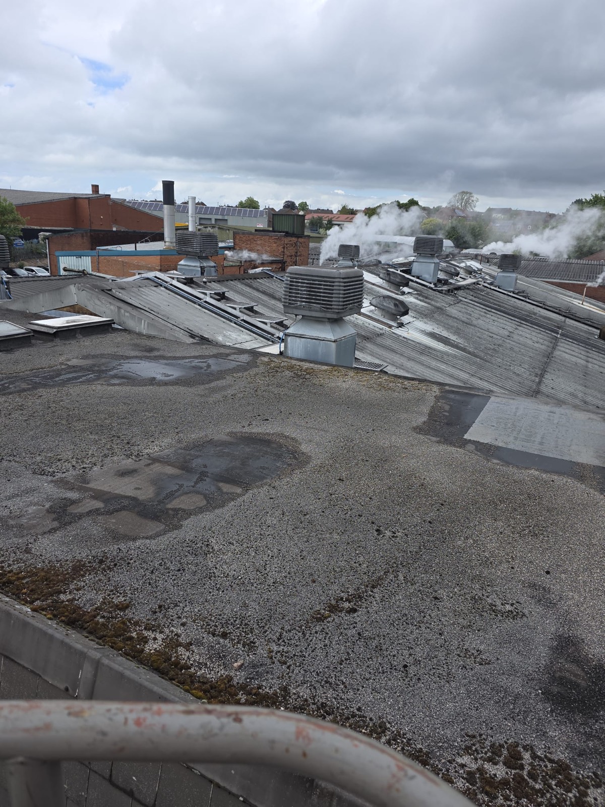 Tired commercial flat roof in Heanor with gravel, moss and ponding water before refurbishment